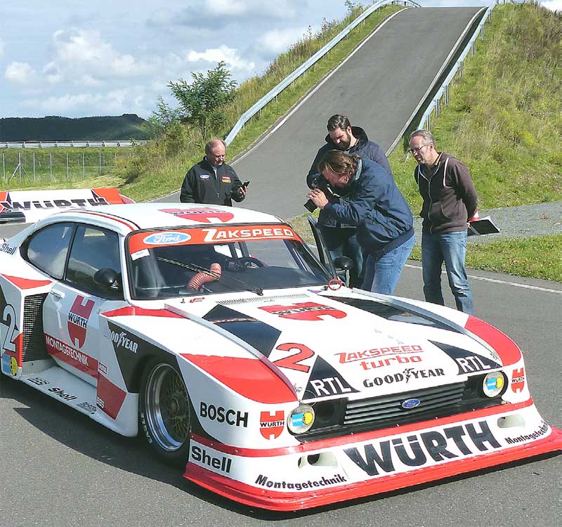 Gemeinschaftliches Arbeiten: Für das Foto des Zakspeed-Motors heben Gregor und Lukas Reininger die Haube vom Renner. Rechts im Bild geht das AUTO BILD KLASSIK-Team seiner Arbeit nach: Christian Bittmann fotografiert, Marc Keiterling (rechts) denkt stets über die richtigen Formulierungen nach und Tim Dahlgaard vermisst und wiegt die Autos. Links ist Wolfgang Laufer zu sehen, der „Vater“ der Ford Classic Cars in Köln. Gemeinschaftliches Arbeiten: Für das Foto des Zakspeed-Motors heben Gregor und Lukas Reininger die Haube vom Renner. Rechts im Bild geht das AUTO BILD KLASSIK-Team seiner Arbeit nach: Christian Bittmann fotografiert, Marc Keiterling (rechts) denkt stets über die richtigen Formulierungen nach und Tim Dahlgaard vermisst und wiegt die Autos. Links ist Wolfgang Laufer zu sehen, der „Vater“ der Ford Classic Cars in Köln.
