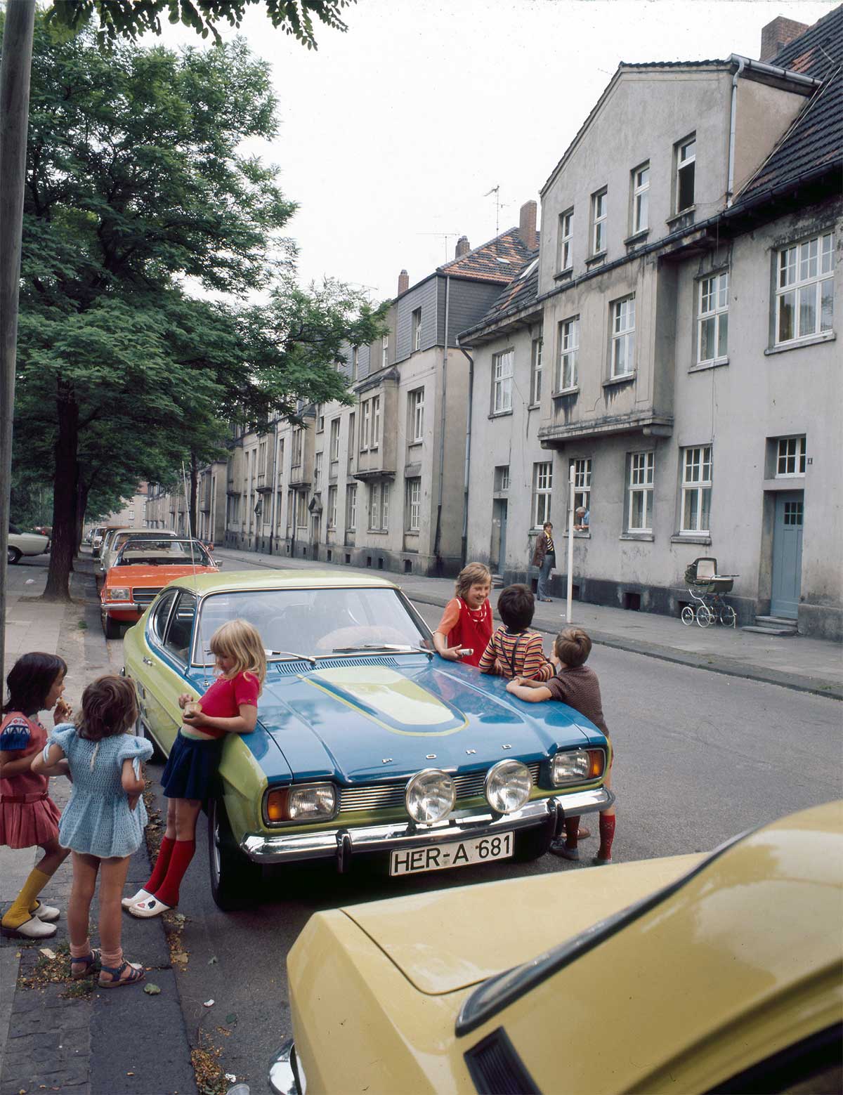 Das Ruhr Museum Essen zeigt bis zum 3. Oktober „Kindheit im Ruhrgebiet“. Dort ist dieses Bild von Manfred Ehrich zu sehen, aufgenommen 1975 in Herne. Offen bleibt die Frage, ob der Besitzer des Autos die Belagerung seines Wagens lässig nahm. Oder ob auf der gegenüberliegenden Straßenseite einige Sekunden später ein Fenster aufflog und etwas in dieser Art hinausgebrüllt wurde: „Ey, ihr Blagen, weg da von meine Karre! Imma die gleichen Fisimatenten mit euch, verdammt nomma. Ich komm` euch gleich da raus und dann gibbet wat auffe Löffel!“ Das Ruhr Museum Essen zeigt bis zum 3. Oktober „Kindheit im Ruhrgebiet“. Dort ist dieses Bild von Manfred Ehrich zu sehen, aufgenommen 1975 in Herne. Offen bleibt die Frage, ob der Besitzer des Autos die Belagerung seines Wagens lässig nahm. Oder ob auf der gegenüberliegenden Straßenseite einige Sekunden später ein Fenster aufflog und etwas in dieser Art hinausgebrüllt wurde: „Ey, ihr Blagen, weg da von meine Karre! Imma die gleichen Fisimatenten mit euch, verdammt nomma. Ich komm` euch gleich da raus und dann gibbet wat auffe Löffel!“
